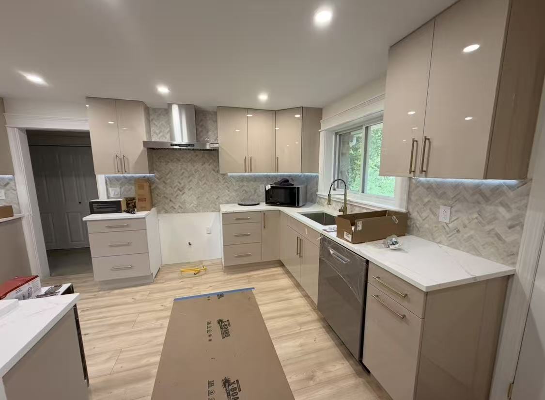 Sample 106G glossy taupe flat-panel cabinets with white countertops and a herringbone tile backsplash