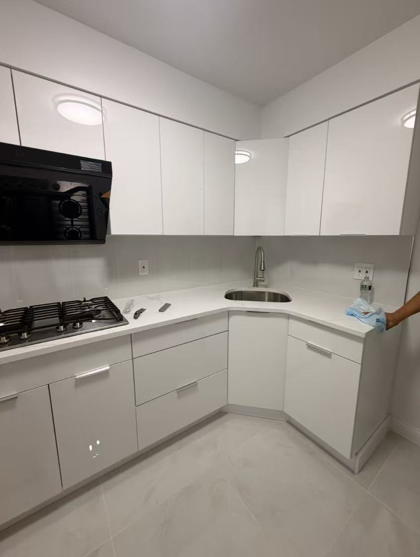 Sample 8805 glossy white flat-panel cabinets in a compact kitchen with white countertops and silver hardware