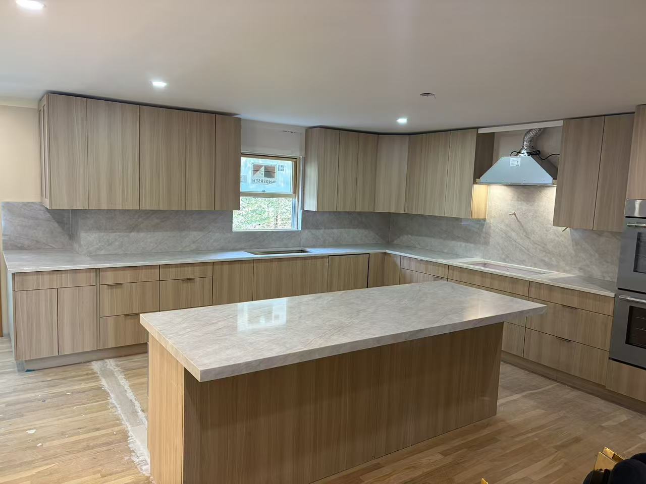 Sample T300 light wood-grain flat-panel cabinets with a marble-look island, countertops and full-height backsplash
