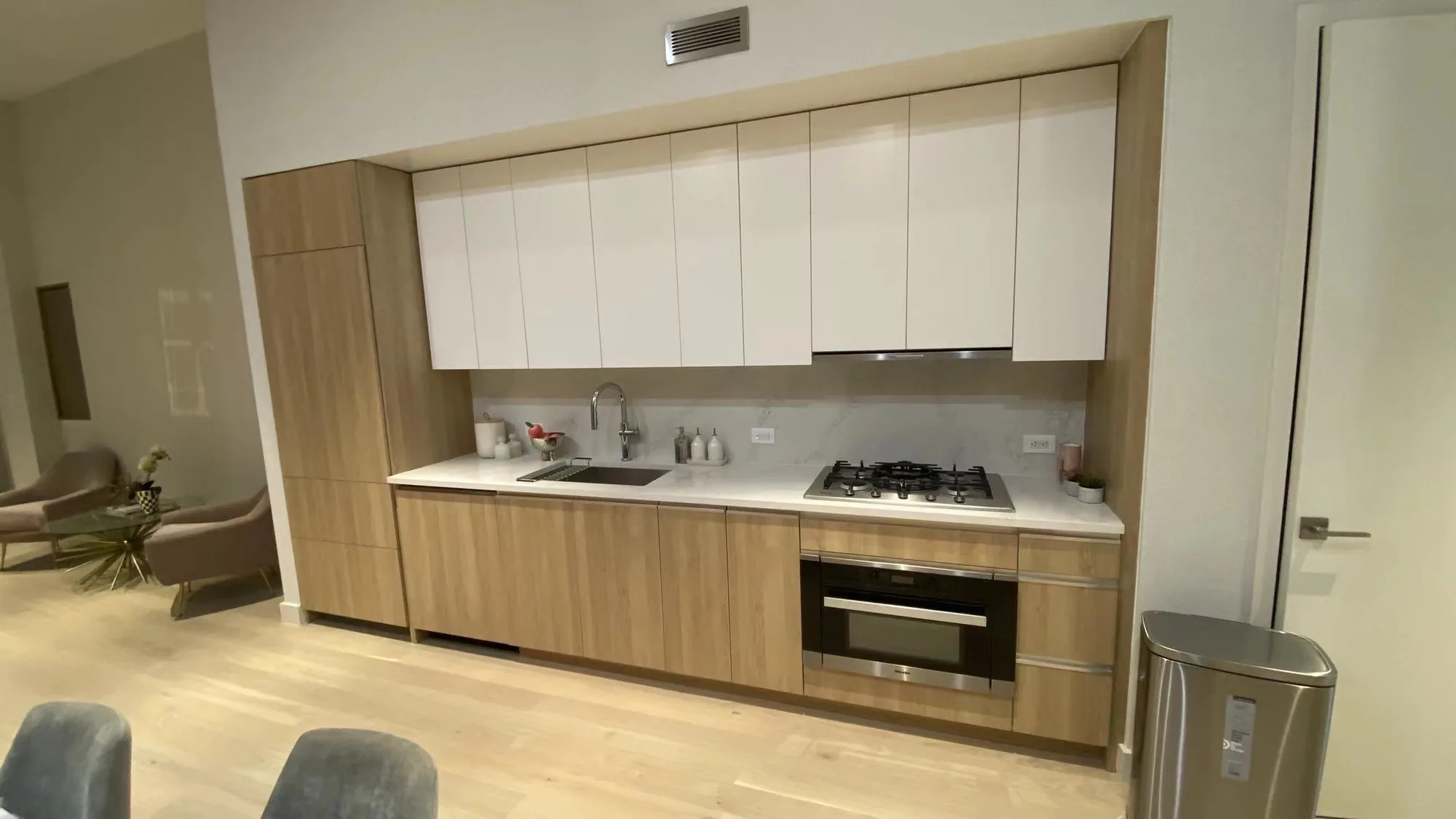 Compact flat-panel kitchen with white upper cabinets and light wood base cabinets