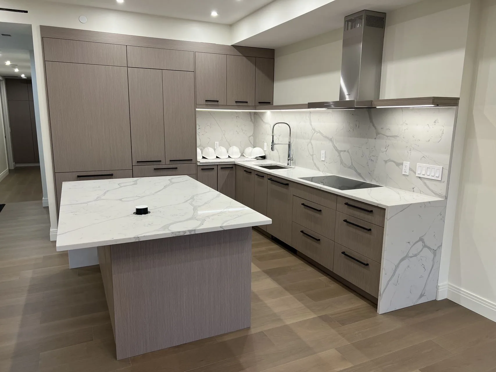 Taupe modern kitchen with an island and waterfall stone end panels